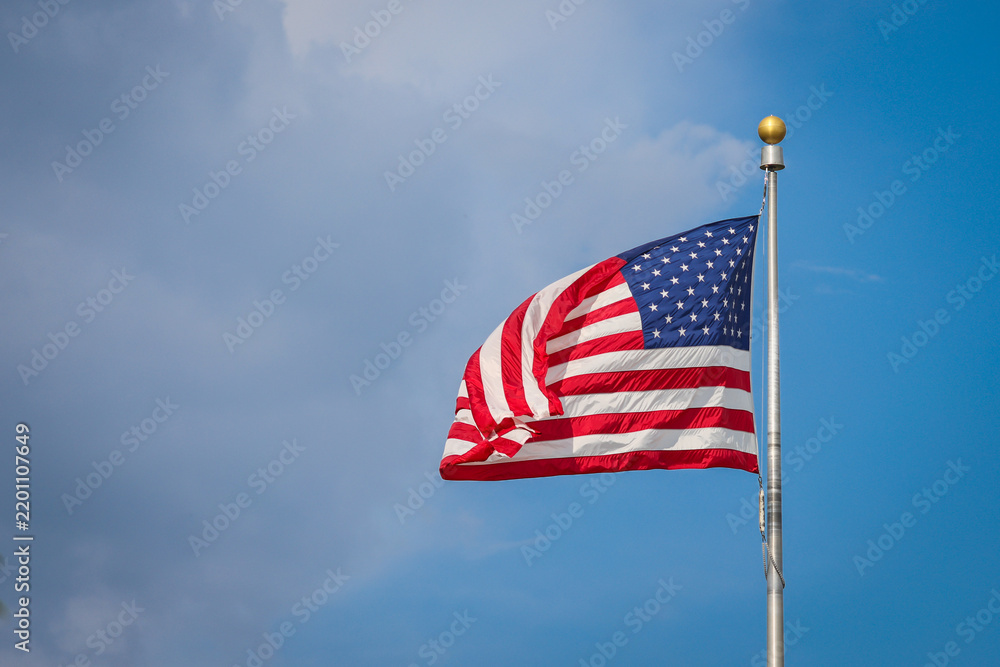 Obraz premium The United States of America flag waving in the wind on a sunny day
