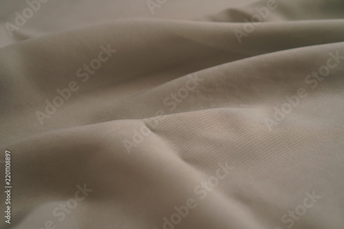 Soft gray fabric drapes elegantly with gentle folds. Light catches subtle texture and natural creases. Minimalist tone suits modern fashion or interior design. Perfect for backgrounds