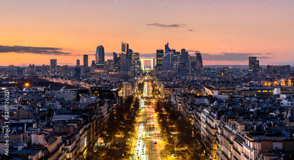 Fototapeta premium Panoramic view of the La Defense financial district and avenue traffic in Paris, France at sunset with illuminated skyscrapers.