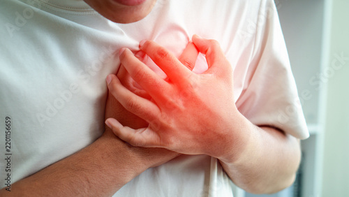 Fotografie Close-up of a person clutching the chest with a red highlighted pain area, illustrating sudden chest discomfort, cardiac symptoms, cardiovascular risk, medical emergency, and heart health