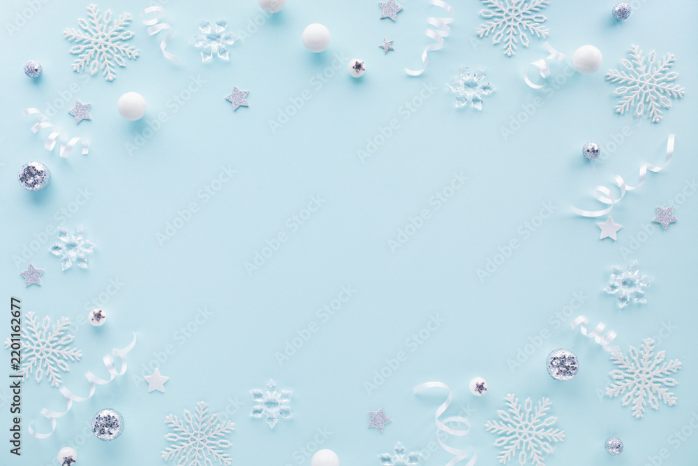 Obraz premium Festive Christmas and New Year holiday frame border from white snowflakes, silver baubles ornaments and winter decoration top view.
