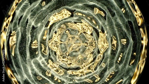 Cymatics wave patterns created by sound frequencies in liquid, forming complex symmetrical golden structures and concentric ripples on a dark background.