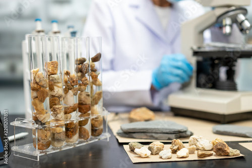 Fotografía Geologist examines rock and mineral samples in test tubes beside a microscope in a modern laboratory, supporting research, testing, and scientific analysis