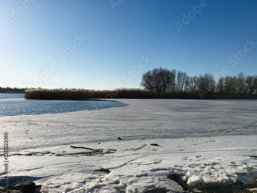 Foto River shore with melting snow on broken ice and freed waters flowing in calm tid
