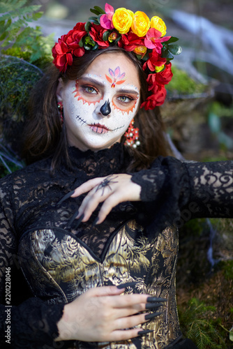 Halloween beauty portrait of young woman in nature. Female face adorned with Santa Muerte makeup.