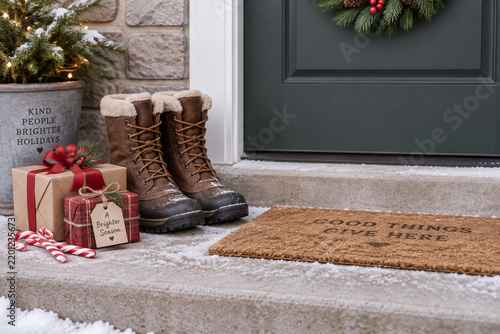 Wrapped gift boxes and candy canes by winter boots, holiday giving concept