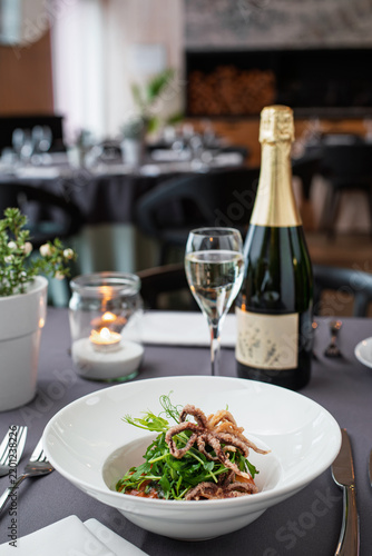 Canvas Print Gourmet octopus salad with sparkling wine at restaurant table