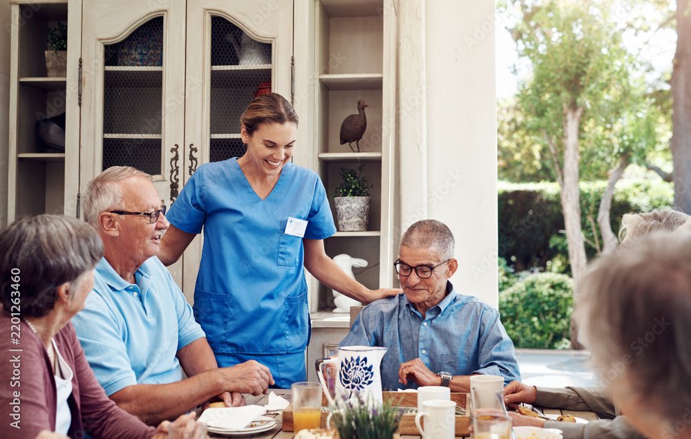 Obraz premium Smile, caregiver and old people at house with food, assistance and social gathering for tea party. Happy, nurse or senior friends in dining room with snack, assisted living and sweet treat for health