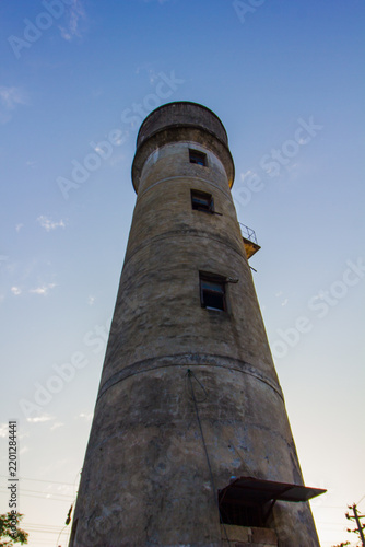 Maritime navigation and coastal safety, old stone lighthouse tower against a clear blue sky