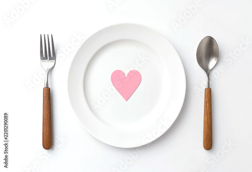 White plate with pink heart symbol surrounded by wooden handled utensils