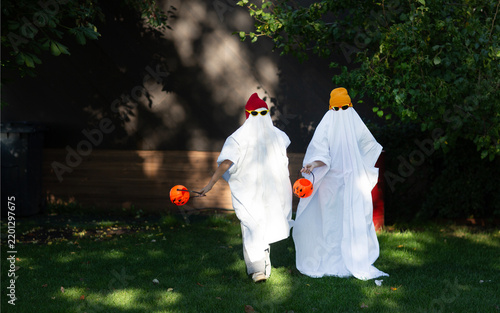 two kid in Halloween ghost costumes Wearing bright hats and black glasses,  in the park. Halloween party