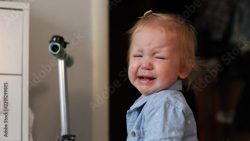 Quadro su tela A distressed toddler crying with eyes closed while wearing a light blue button d