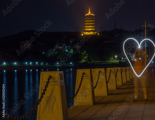 Travel and romance concept, light painting heart shape at night near ancient pagoda