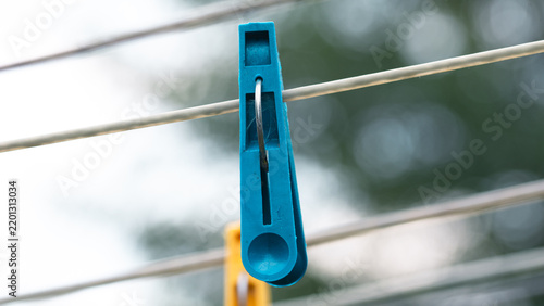 One Blue Plastic Clothespin Holding A Metal Wire Against Blurred Background
