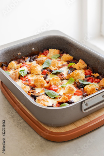Freshly Baked Eggplant Casserole Garnished with Basil Leaves and Cheese in a Baking Dish