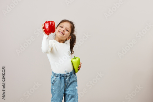 Little girl promoting healthy eating with bell peppers