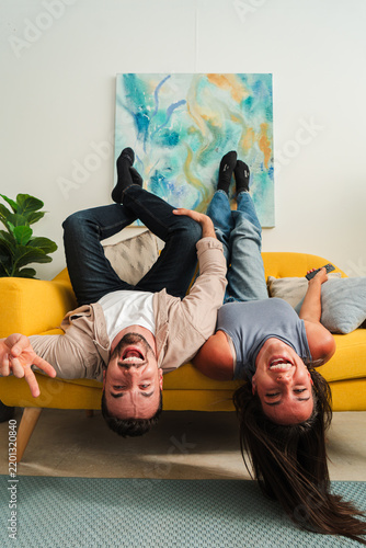 Foto A candid shot of a couple hanging upside down from a sofa, sharing wide smiles and playful energy