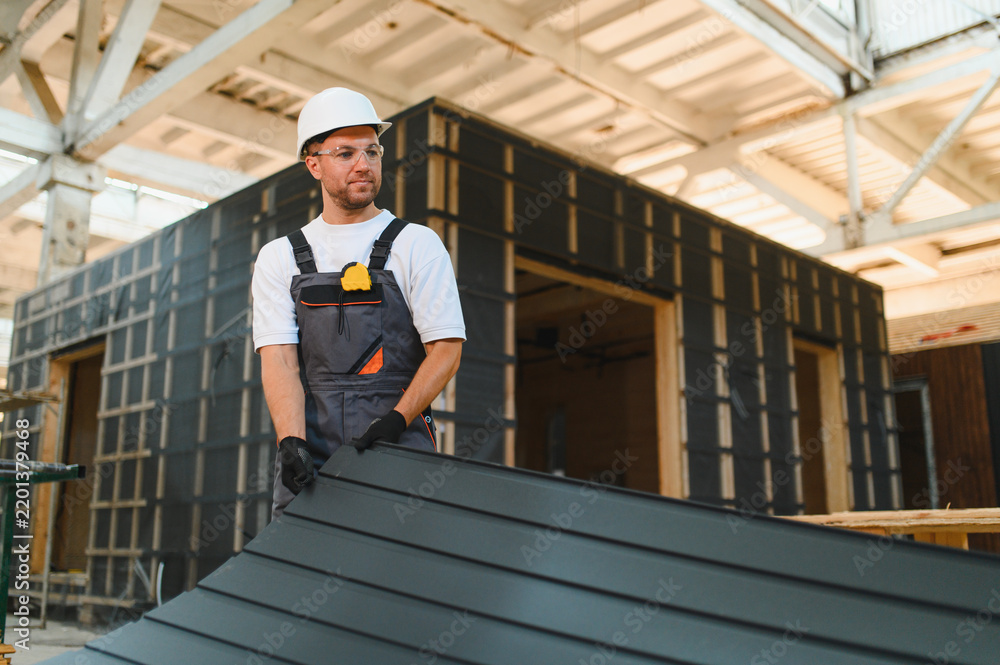 Obraz premium Worker installing siding on modular house in factory
