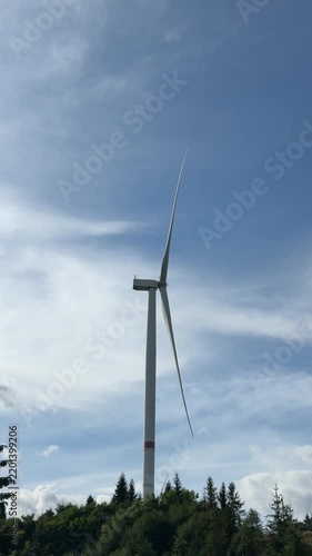 Wind Turbine Rising Above Forested Hills Under Sky