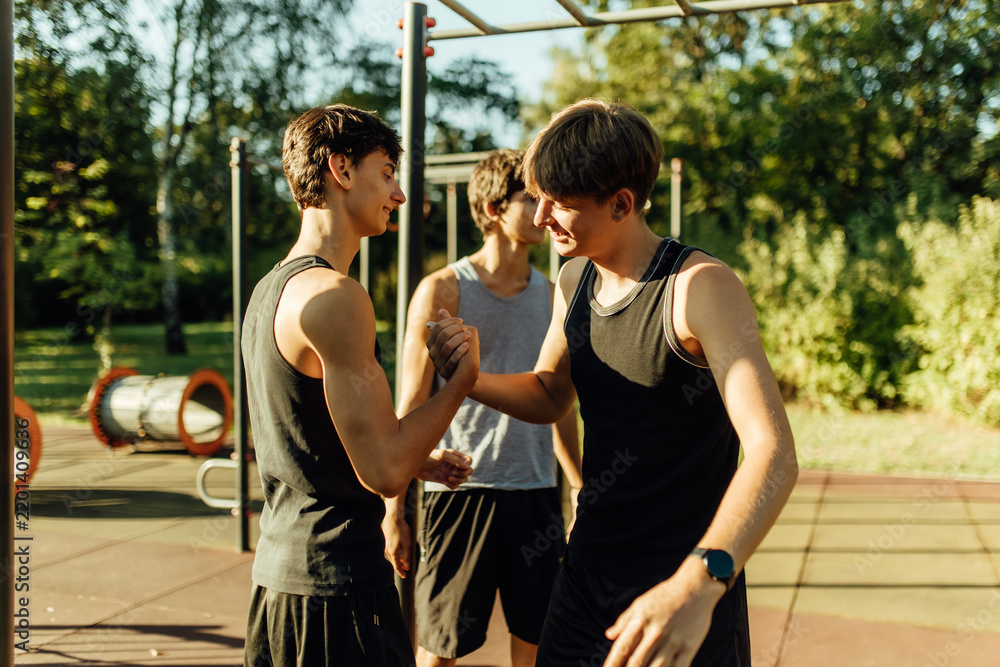 Obraz premium Teenager boys shaking hands together at the street fitness park.