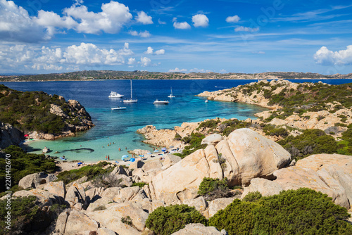 Capsized cove with boats and swimmers on the rocky coast of caprera