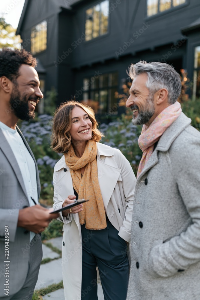 Obraz premium Friendly real estate consultation with agent and two clients outside a modern home by landscaped garden for brochure and listing