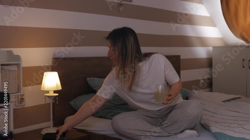 Woman in pajamas using her smartphone in bed at night