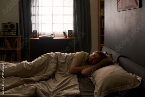 Young adult Caucasian man sleeping in bed resting during morning routine. Visual concept suitable for sleep health, wellness campaigns and insomnia treatment marketing