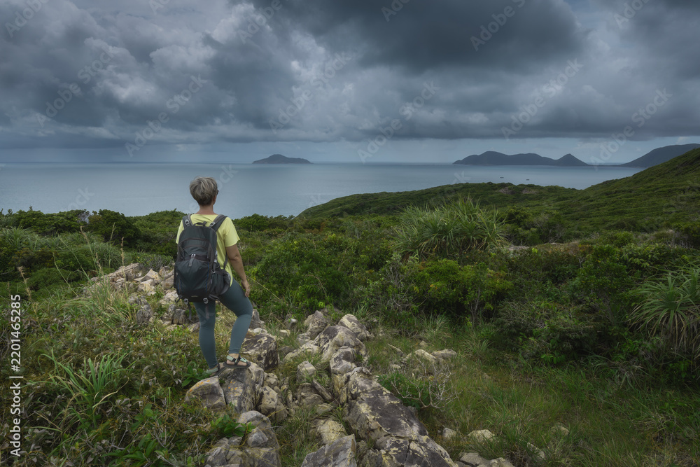 Obraz premium Female hiker observing distant islands of the Con Dao archipelago from a coastal viewpoint in Dam Tre Bay, Vietnam
