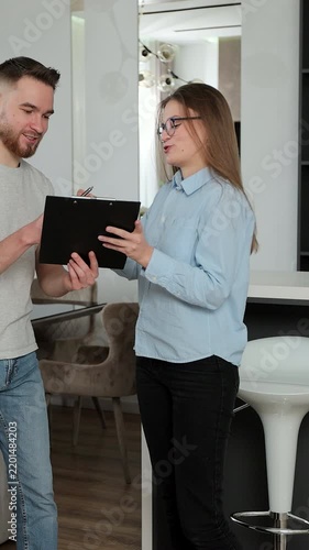 Vertical video. Real estate agent sign contract and giving home keys to happy couple. Couple moving to new apartment. Real estate concept.