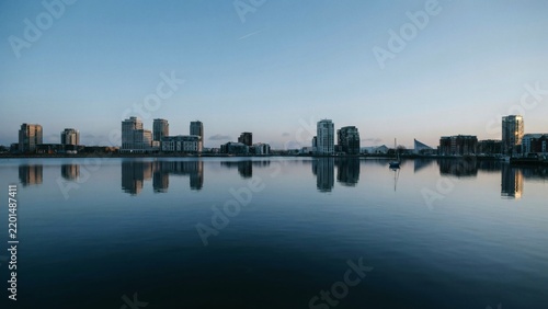 Modern city skyline with high rise buildings reflected in calm water during early evening with creating serene urban scene captures tranquil cityscape