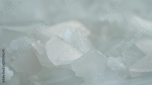 Crystalline bischofite flakes, natural magnesium chloride mineral salt, in macro view, use in spa treatments, cosmetology, balneotherapy, skincare routines. Cosmetic bischofite magnesium salt flakes
