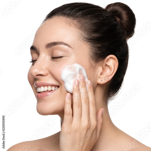 Woman applying facial foam cleanser, enjoying skincare routine, smiling with eyes closed