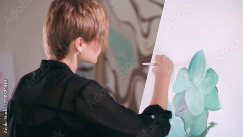 The artist paints a picture. A woman applies paint to a canvas with a brush in the studio.