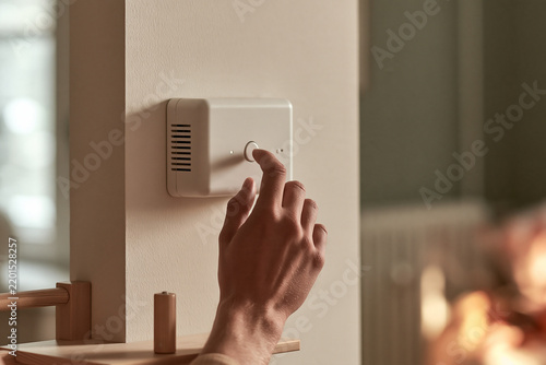 Hand adjusting a thermostat in a modern home setting  
