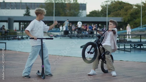 Two Boys Performing BMX Bicycle and Scooter Tricks in Skate Park