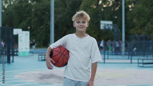 Portrait of 10 Year Old Curly Boy Holding Basketball Ball Outdoors