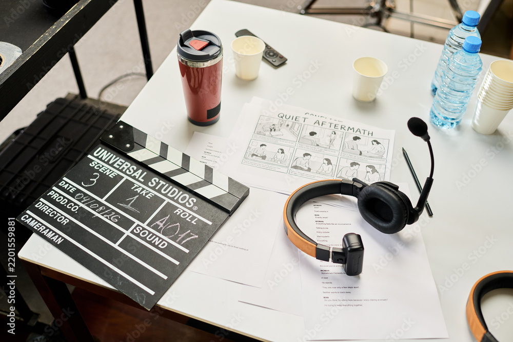Obraz premium High angle shot of clapperboard, storyboard, script, and headphones on table during film preproduction. Useful for cinematography and media projects