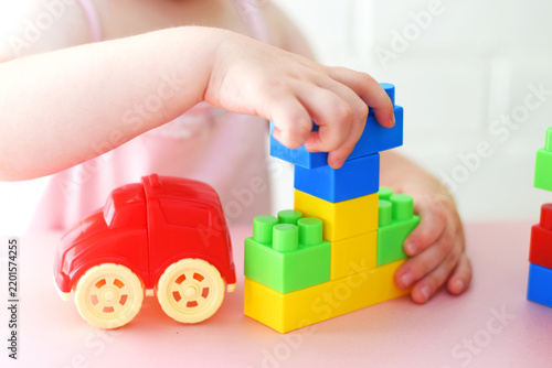 Child playing with colorful plastic building  constructor blocks and toy car at a table. for neurodevelopmental materials, early learning ads, preschool promotions, parenting blogs, and toy catalogs.