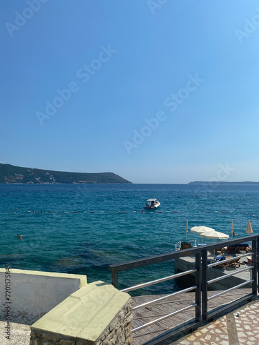 High-angle view of the calm turquoise sea along the coast of Herceg Novi, Montenegro, under a clear blue sky