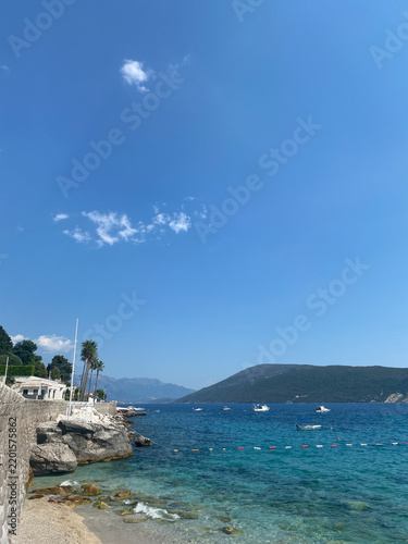 Scenic view of a rocky coastline in Herceg Novi with clear turquoise water under a bright blue sky