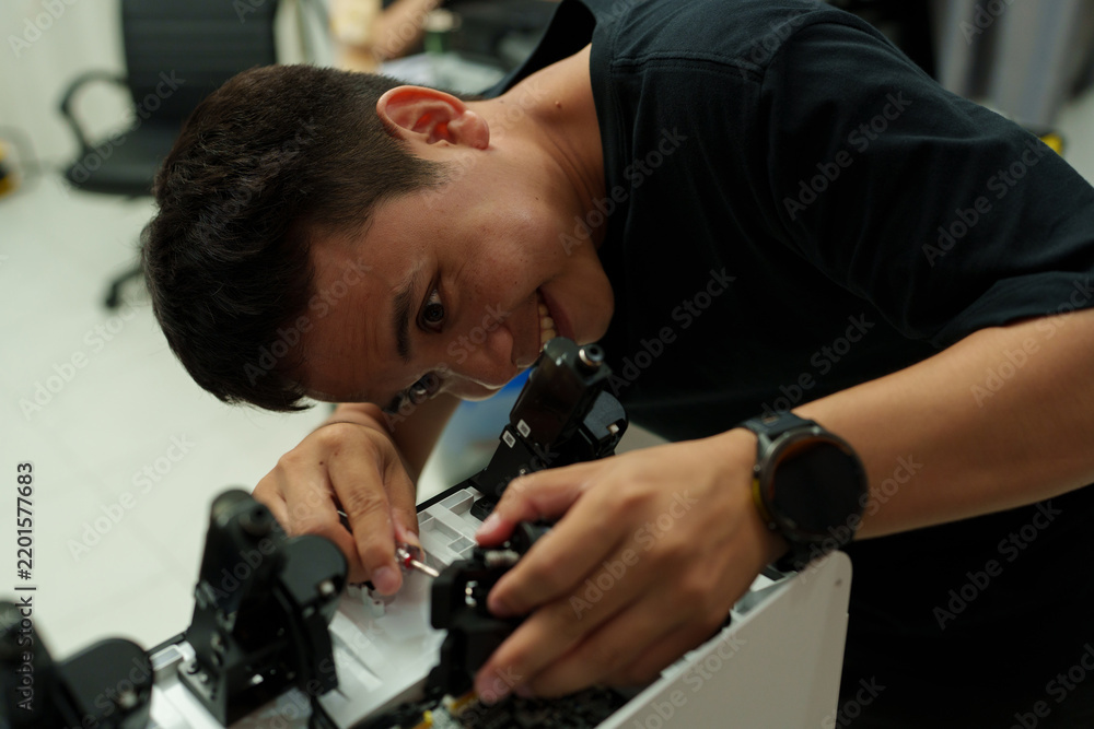 Fototapeta premium The focus is on the hands of a technician setting up a 3D printer to print a clear white plastic model, using cutting-edge technology and concentrating on specific points within the laboratory.