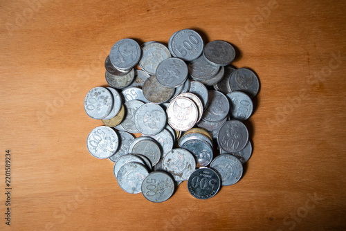 Stacked silver coins rest on warm wooden surface