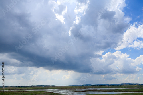 Dramatic cumulus clouds with sunbeam breaking through blue sky 