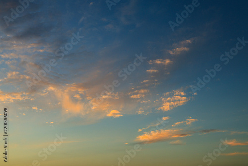 Golden sunset clouds floating in blue sky at dusk 
