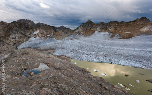 Views of a glacier melting into a lake in a rugged mountain landscape during cloudy weather, Austria