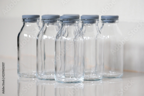 Close-up of empty clear glass bottles with grey rubber caps