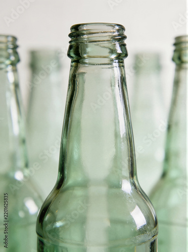 Close up of a clear glass bottle shoulder and neck with threaded rim