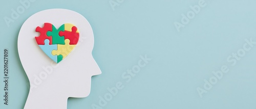Human head silhouette with colorful puzzle heart on light blue background
