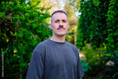 headshot of Young latino man looking at camera outdoors in park